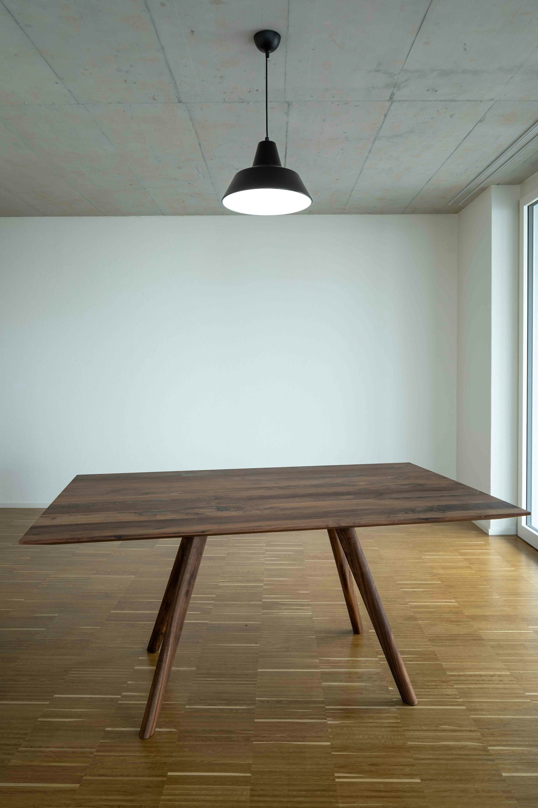 A minimal, empty room with a single wooden table, evoking space for a strategic conversation.